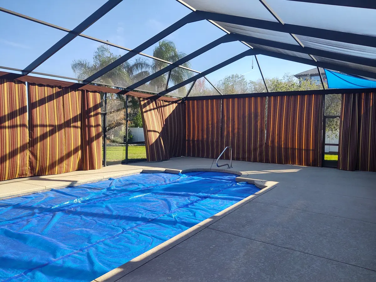 Striped privacy curtains around pool with blue shade sail