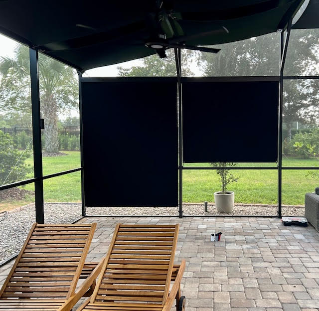 Dark navy roller shades on lanai with wooden loungers