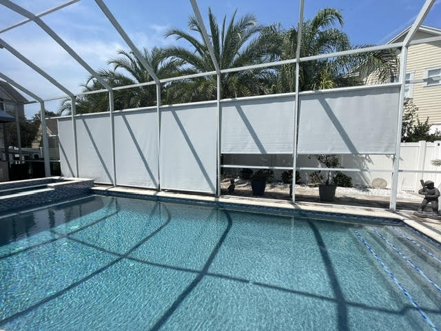 White roller shades around swimming pool with palm trees