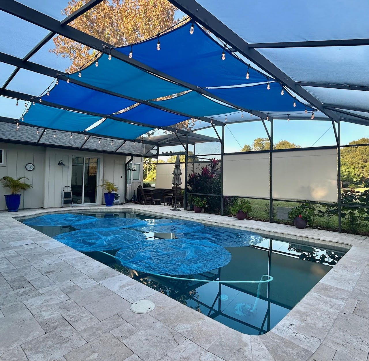 Lagoon blue shade sails over pool with string lights